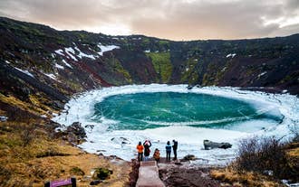 Un groupe de voyageurs profite de la vue sur le lac gelé du cratère de Kerid en hiver en Islande.