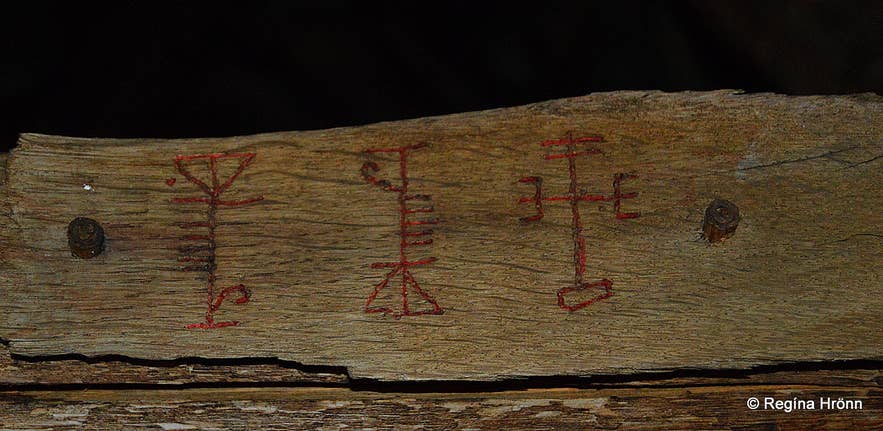 Red galdrastafir magical staves carved into aged wood, used in Icelandic sorcery for protection and luck.