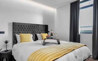 A double bed with a tray with two glasses of champagne and strawberries at Alva Apartments.