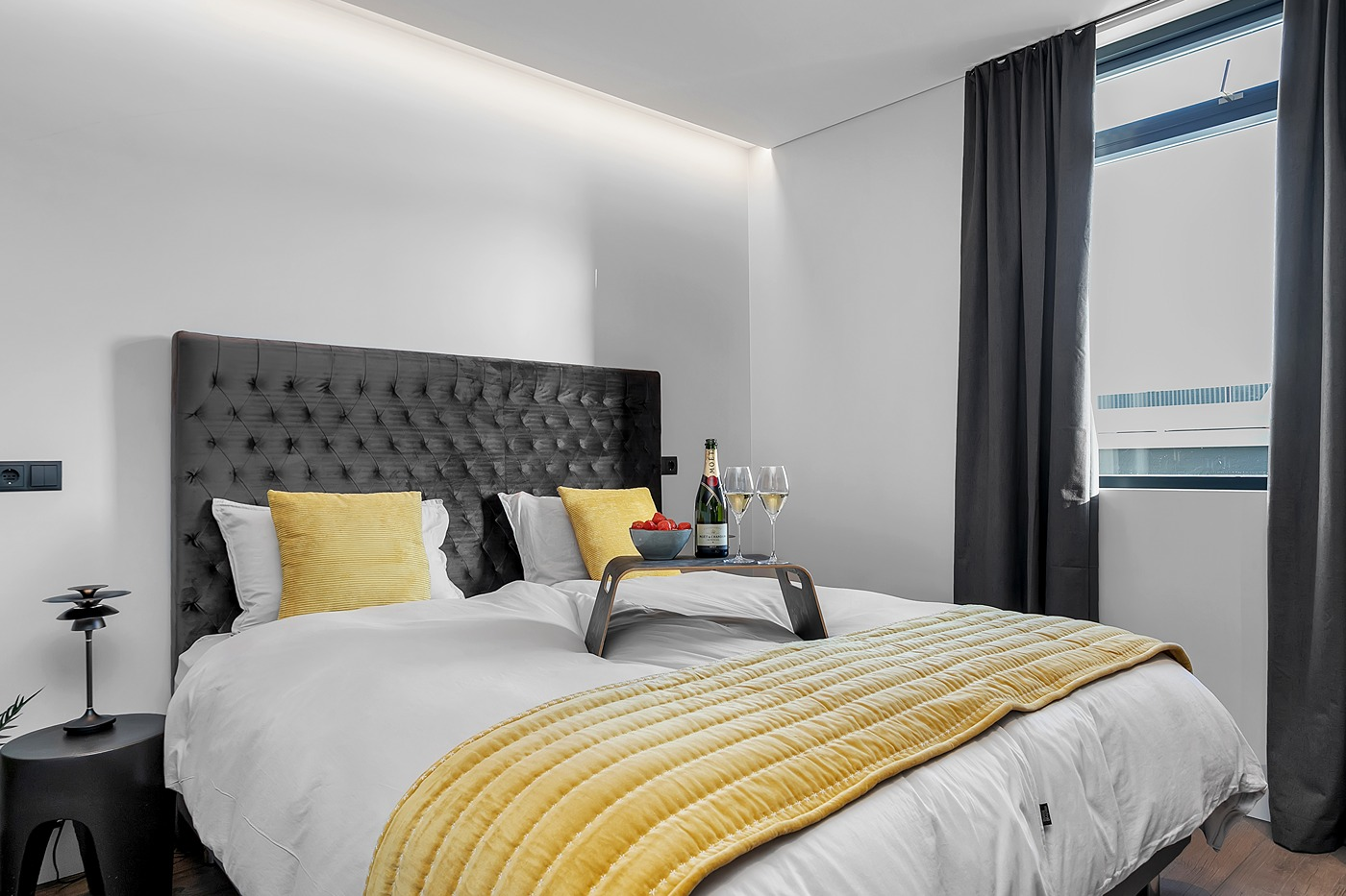 Een tweepersoonsbed met een dienblad met twee glazen champagne en aardbeien bij Alva Apartments.