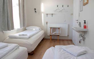 A triple room with three single beds and a place to hang clothes at 1908 Hostel By Ourhotels.