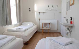 A triple room with three single beds and a place to hang clothes at 1908 Hostel By Ourhotels.