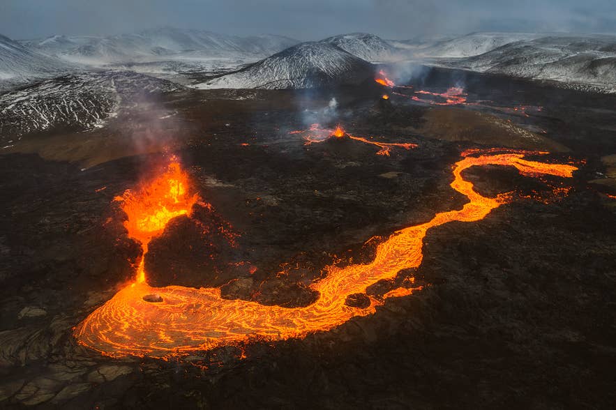 Aerial view of the Fagradalsfjall volcanic eruption with glowing lava flows winding across the Reykjanes Peninsula in Iceland.