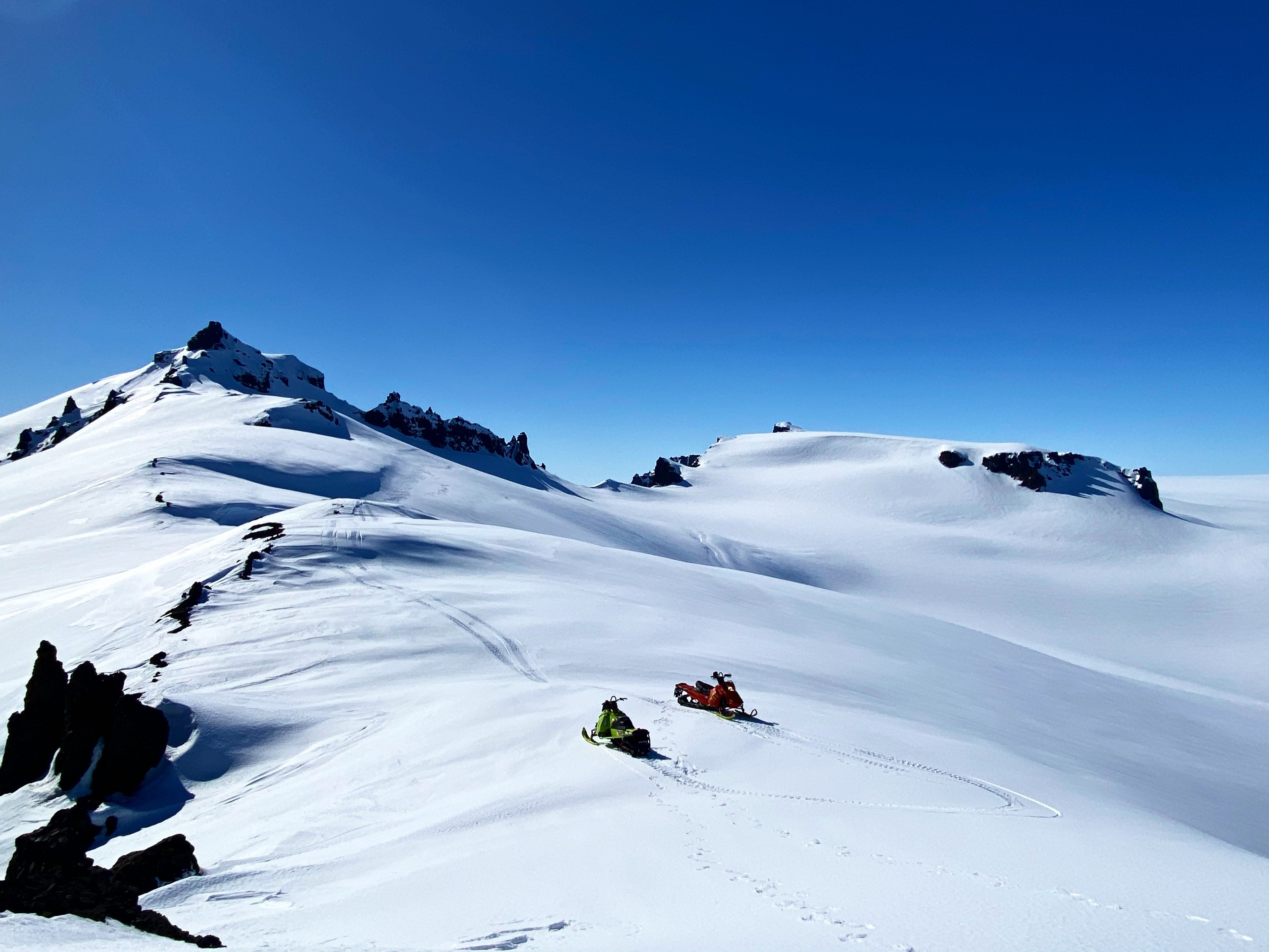 Von oben sieht man zwei Schneemobile ohne Menschen auf dem Gletscher.