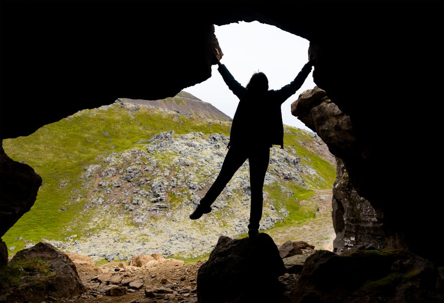 Entrance of the Sönghellir Cave on the Snæfellsnes Peninsula in Iceland with the silhouette of a girl. Volcanic rock in wilderness landscape. Outdoor adventure in remote nature. Entrance of the Sönghellir Cave on the Snæfellsnes Peninsula in Iceland with the silhouette of a girl. Volcanic rock in wilderness landscape. Outdoor adventure in remote nature.