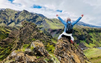A hiker posing for a photo atop a rocky mountain during a hiking tour of Thorsmork.