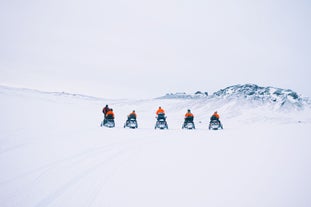 A group of snowmobilers in Iceland exploring the Eyjafjallajokull glacier.