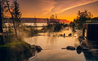 The sun sets over the Forest Lagoon geothermal spa during winter in Iceland.