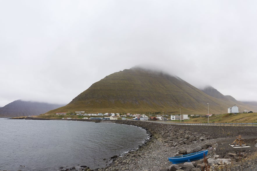 The village of Hnifsdalur in the Icelandic westfjords with a backdrop of mountains and a cloudy sky.