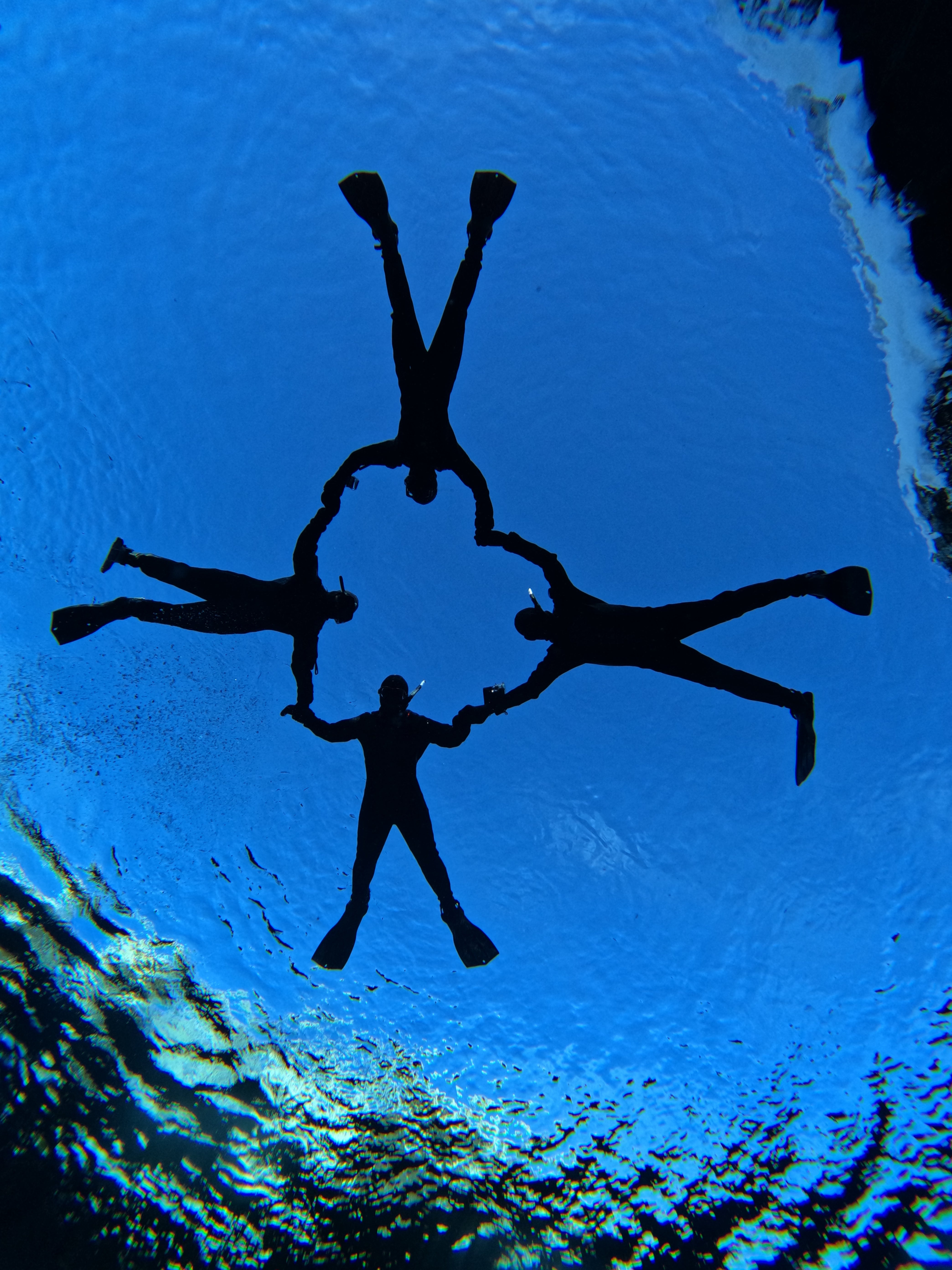 A group of adventurers forming a heart shape while snorkeling in Silfra.