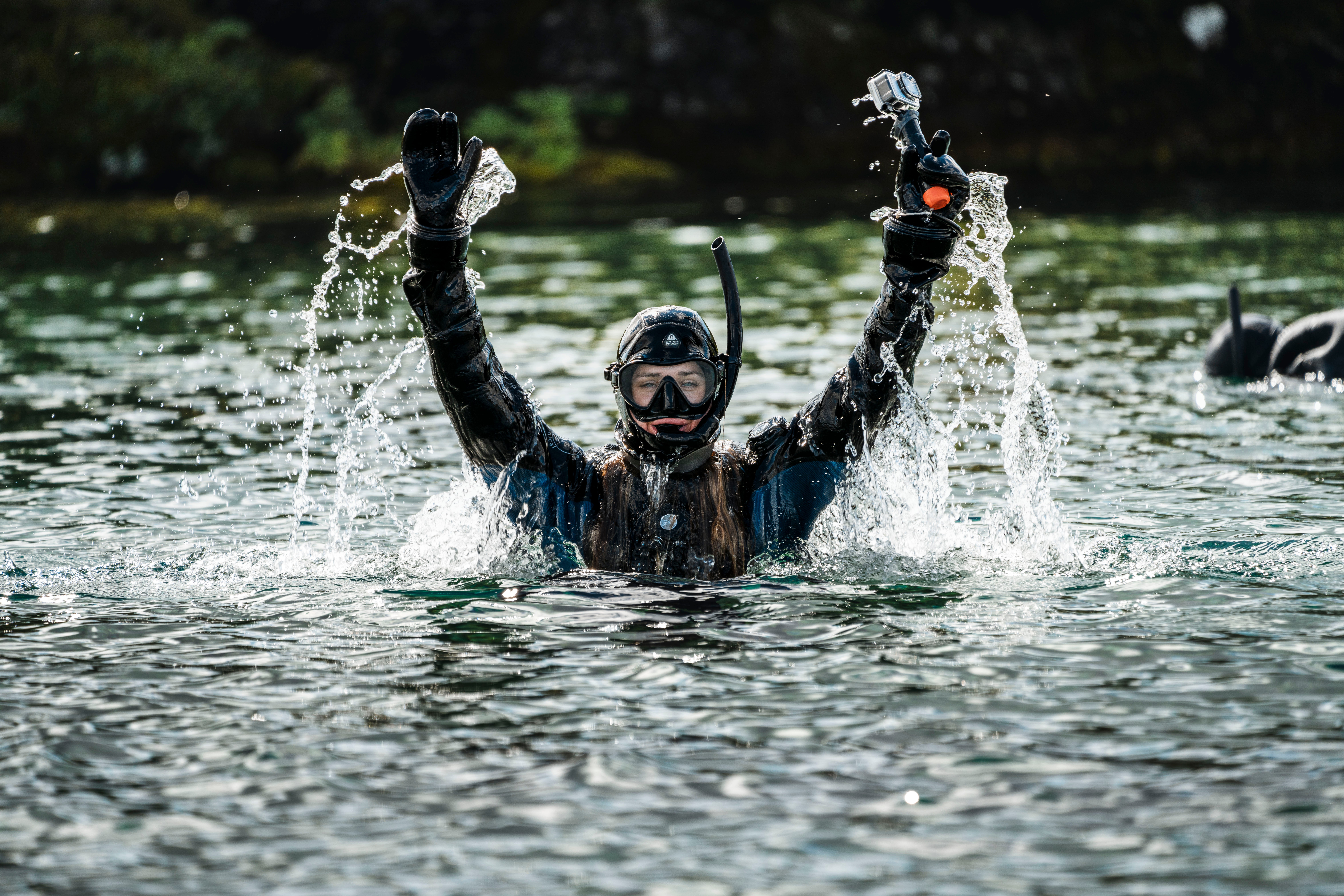 A snorkeler surfaces from the water during a Silfra snorkeling tour in Iceland.