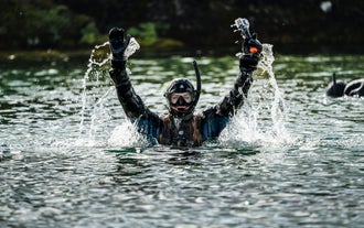 A snorkeler surfaces from the water during a Silfra snorkeling tour in Iceland.