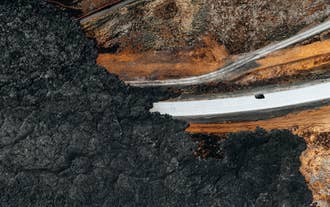 Aerial view of a road near Grindavik, surrounded by dark lava fields and vibrant orange earth in Iceland’s Reykjanes Peninsula.