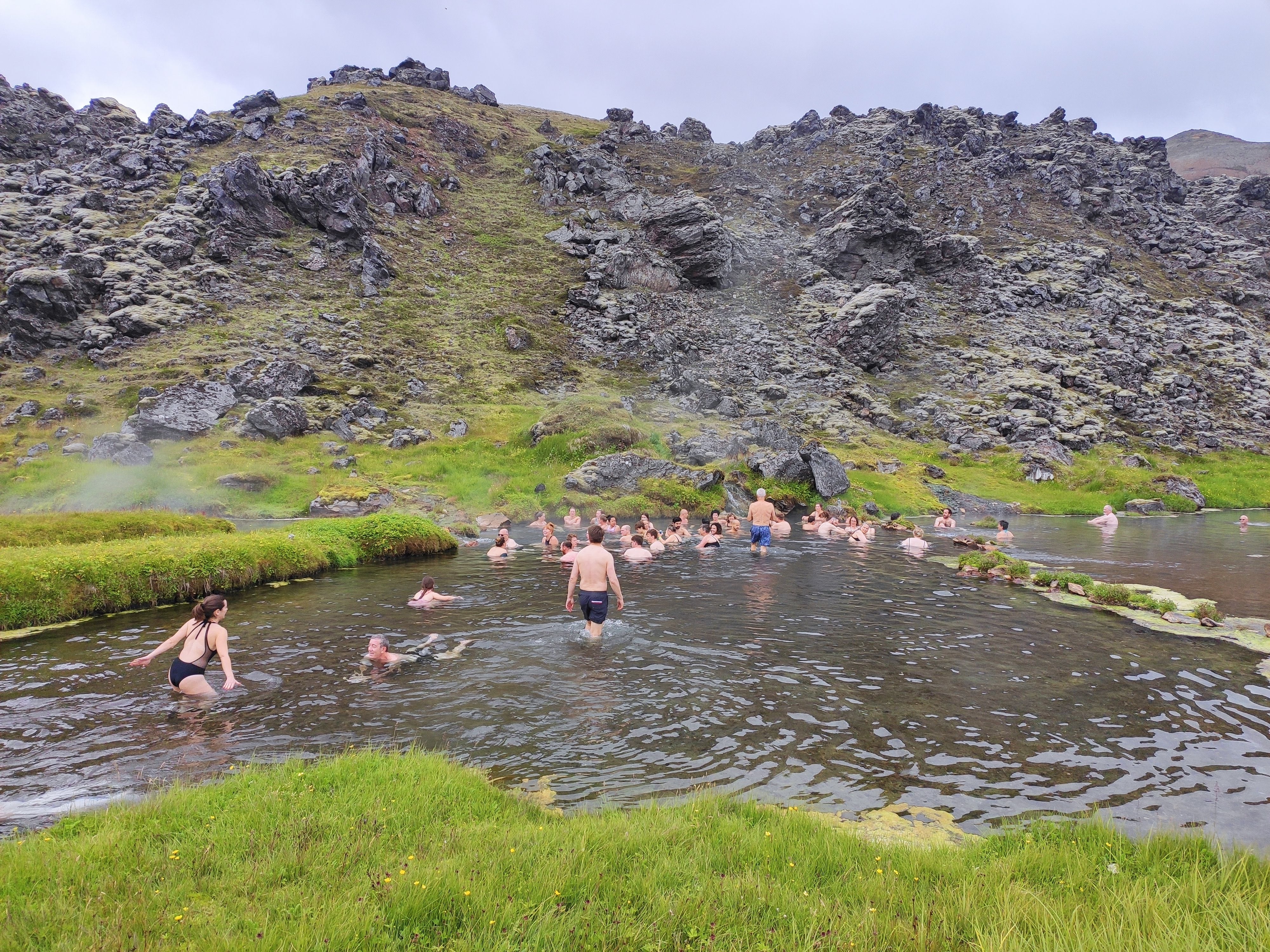 Hikers relax in a natural geothermal river in Landmannalaugar
