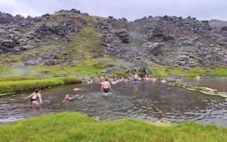 Hikers relax in a natural geothermal river in Landmannalaugar