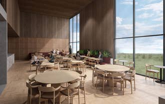 Stilfull lounge på Hotel Loa med trebord, høye vinduer og gjester som spiser eller jobber i en lun, moderne atmosfære.