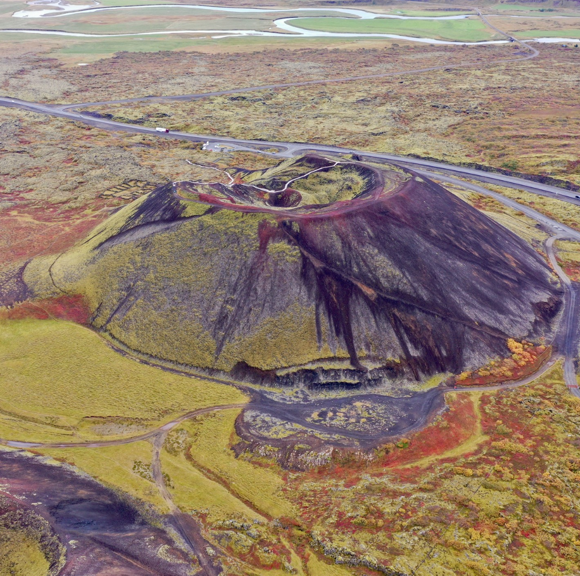 A volcanic crater on the Snaefellsnes Peninsula is characterized by its red sands and mossy green slopes