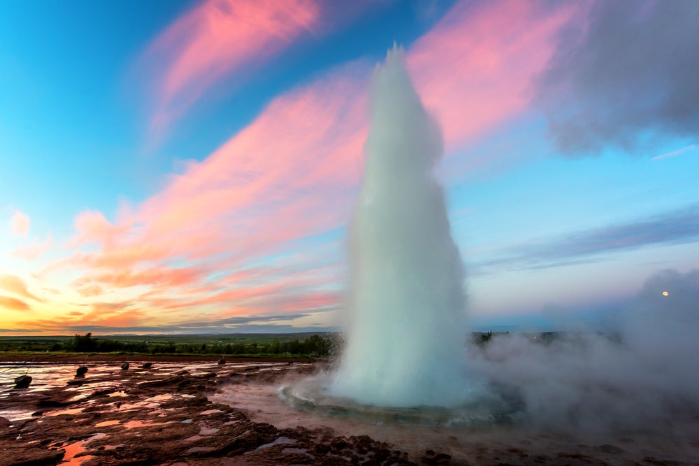 A photo of the Strokkur Geyser erupring hot water into the air.