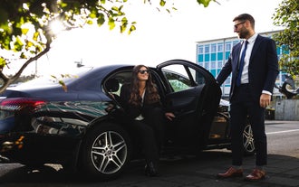 Woman stepping out of a luxury car with a chauffeur’s assistance in Reykjavik.