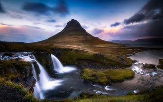 Kirkjufell Mountain and waterfall glowing under a colorful sunset sky in West Iceland.