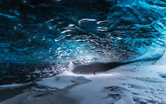 En upptäcktsresande står i beundran inför de hisnande isformationerna i kristallgrottan i Vatnajokull.