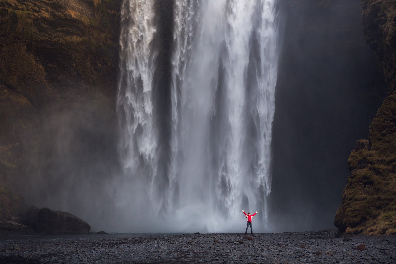 Skógafoss styrter ned med enorm kraft og lager et slør av vanndamp ved foten.