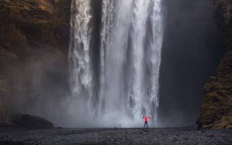Skogafoss Waterfall thunders down with powerful force, creating a misty spray at its base.
