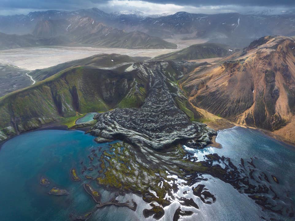 Luftfoto av de røffe lavafeltene og de fargerike rhyolittfjellene i Landmannalaugar på Island.