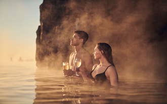 Moment romantique au Sky Lagoon près de Reykjavik, où un couple se détend avec du vin et de la bière dans la piscine chaude.