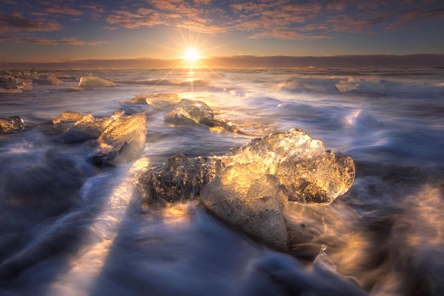 Chunks of ice wash ashore Diamond Beach and shimmer in the sunset. 