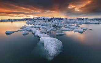 Gli iceberg galleggiano tranquillamente nella laguna glaciale di Jökulsárlón, in Islanda, al tramonto, durante una splendida serata invernale.