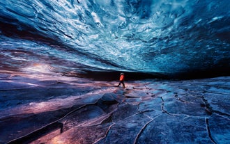A person explores the stunning blue ice cave beneath Vatnajokull Glacier in Iceland during winter.