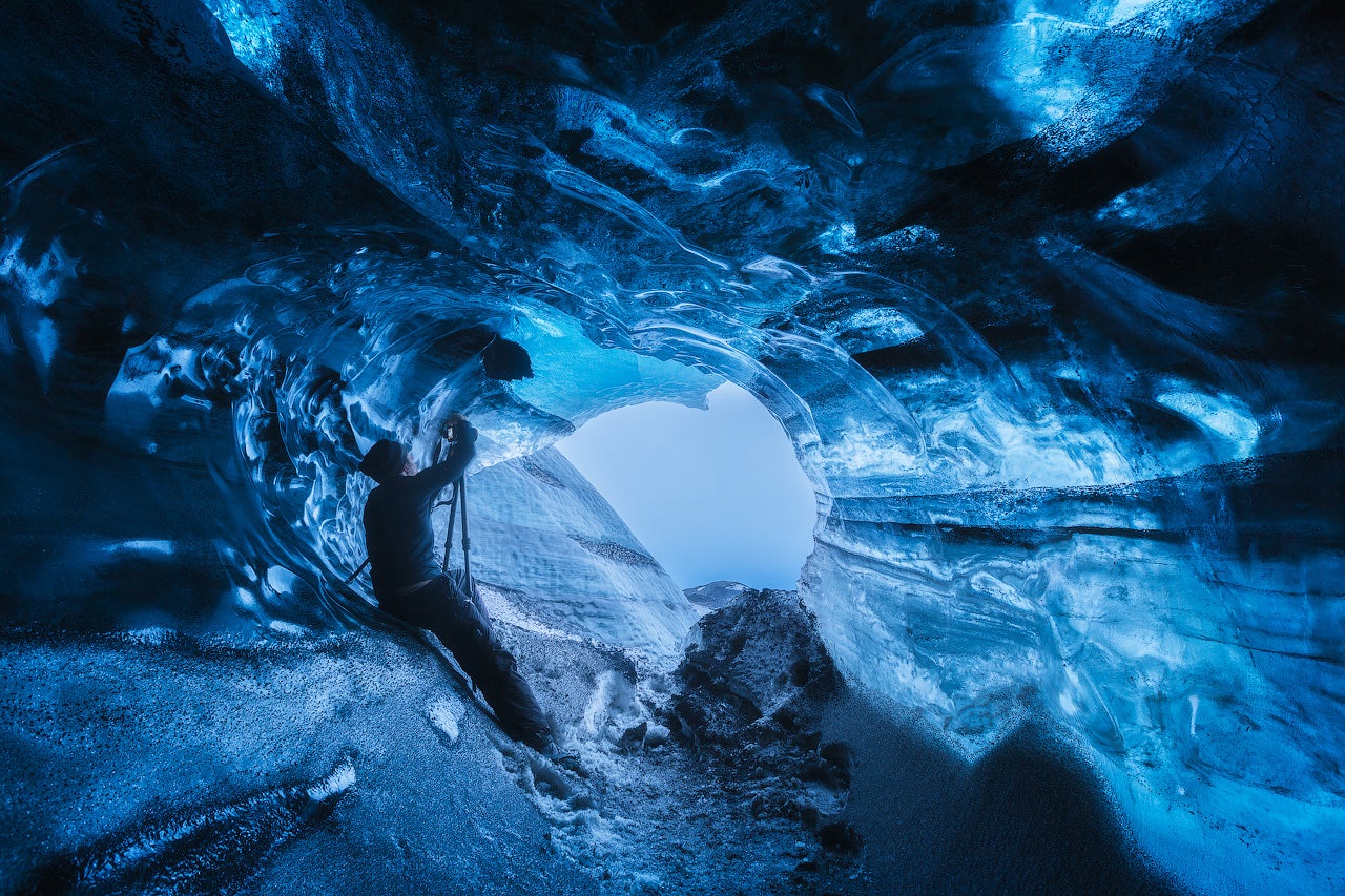 Un homme prend des photos dans une grotte de glace d'un bleu éclatant dans le glacier Vatnajokull, au sud de l'Islande.