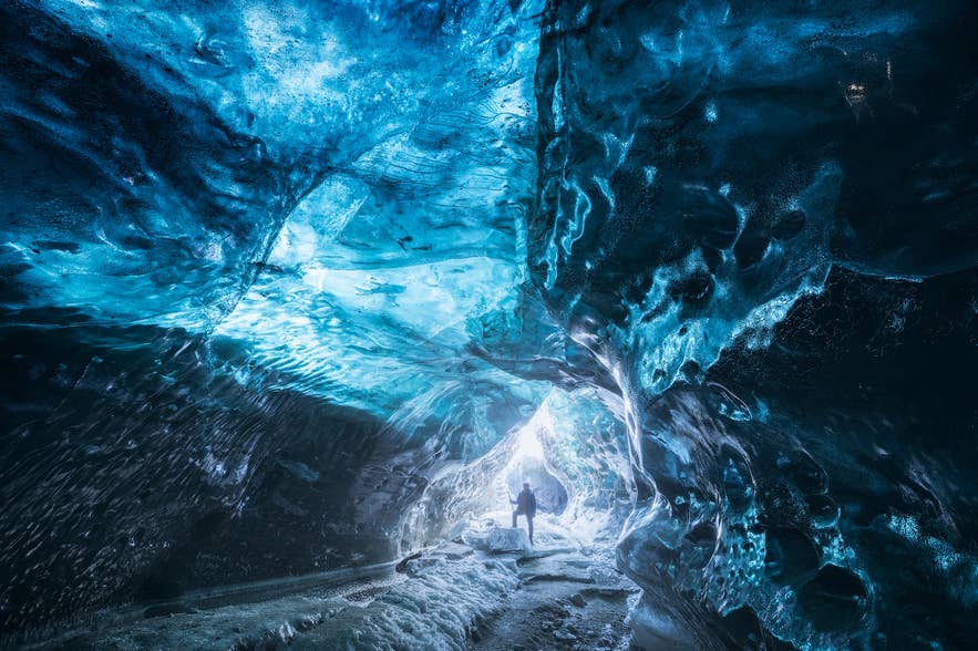 Small figure inside the Katla ice cave in Iceland, showing the scale of the blue ice under Myrdalsjokull Glacier.