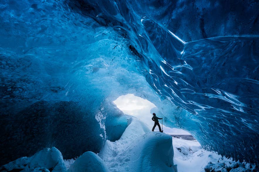 Traveler at the entrance of a blue ice cave Traveler at the entrance of a blue ice cave