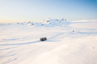 Un turista conduciendo una moto de nieve sobre un glaciar islandés, disfrutando de un paisaje invernal escénico.