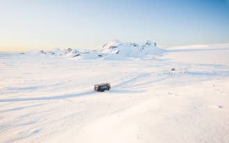 Toerist rijdt op een sneeuwscooter over een IJslandse gletsjer en geniet van het prachtige winterlandschap.