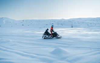Moottorikelkkaseikkailu Langjökullin jäätiköllä Islannissa oppaan ja asiakkaan kanssa talvivarusteissa