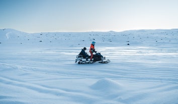 Schneemobilabenteuer auf dem Langjökull-Gletscher in Island mit einem Guide und einem Gast in Winterausrüstung.
