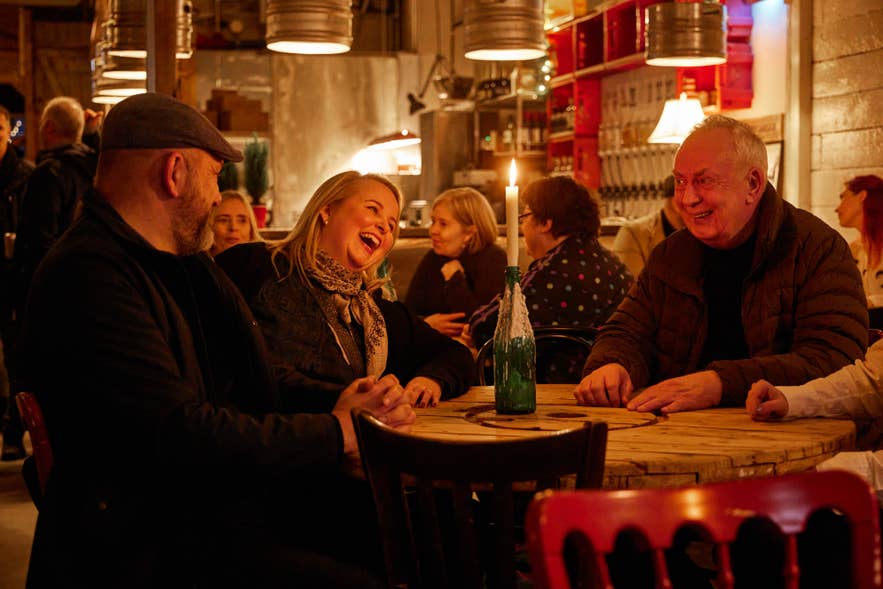 กลุ่มคนกำลังนั่งดื่มที่โต๊ะในร้านคราฟต์เบียร์ยอดนิยม Ægir 220 ฮาฟนาร์ฟยอร์ดูร์