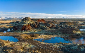 Colorful lava formations and mossy terrain stretch across the Icelandic terrain.