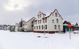 Hrimland Guesthouse in Akureyri, Iceland with red-and-white facade and snow-covered surroundings.