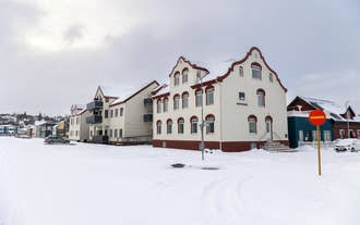 Hrimland Guesthouse in Akureyri, Iceland with red-and-white facade and snow-covered surroundings.