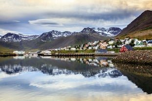 Waterfront view of Siglufjordur village with the mountains behind and the houses reflecting onto the water.