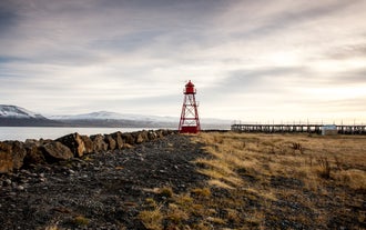 Siglufjordur lighthouse and surrounding landscape on a cloudy day.