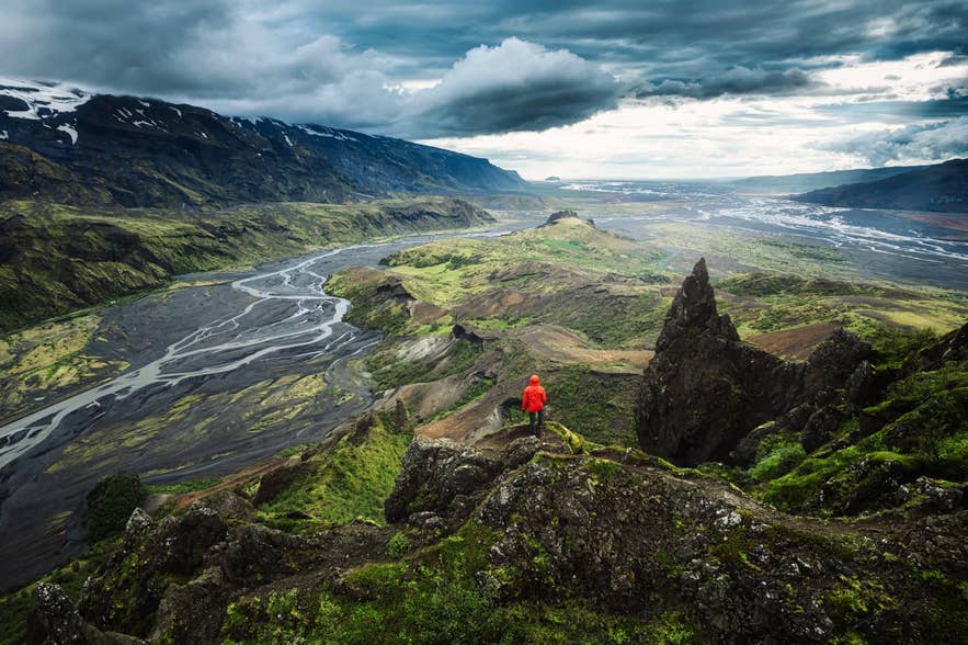 Wandelaar met uitzicht op groene valleien, vulkanische kliffen en gevlochten rivieren in Thorsmork, IJsland. Wandelaar met uitzicht op groene valleien, vulkanische kliffen en gevlochten rivieren in Thorsmork, IJsland.