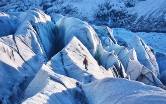 An explorer on a glacier hike is surrounded by shimmering ice formations and dramatic, frozen landscapes.