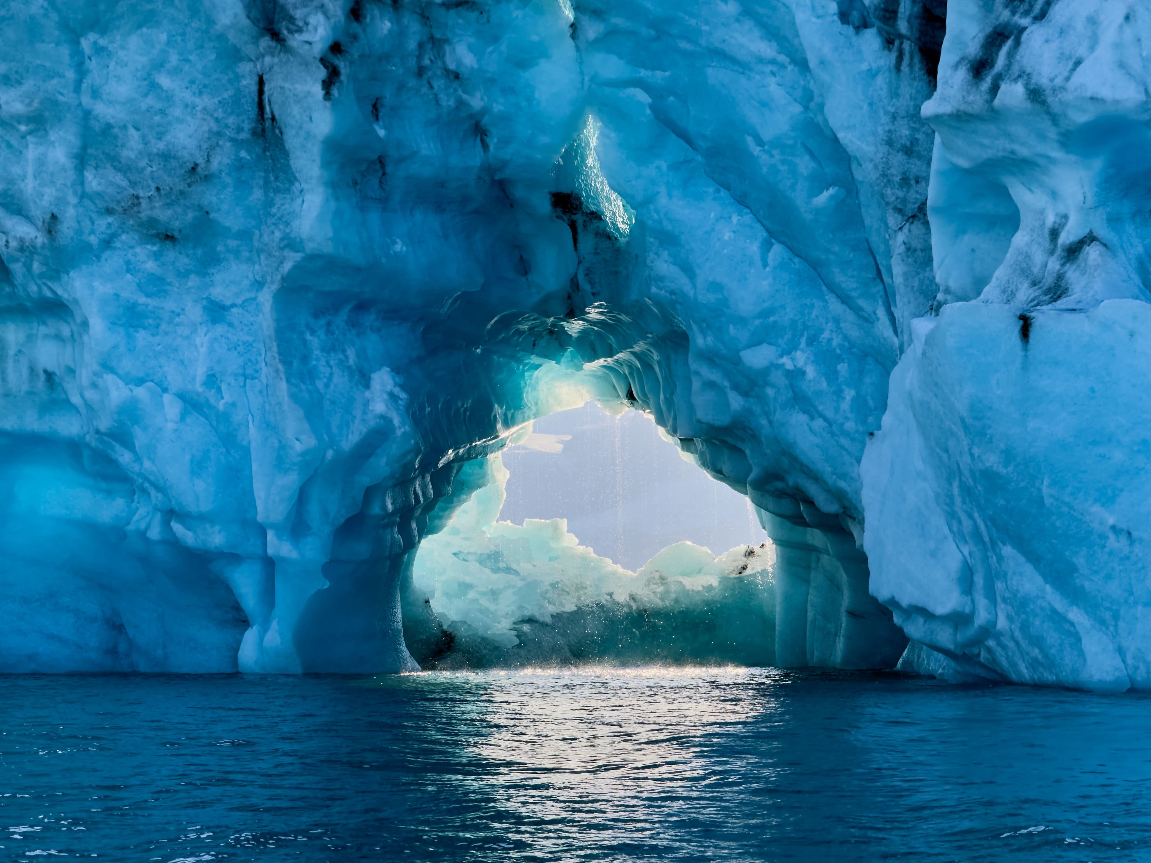 Light shines through a natural ice arch inside a glacier cave at Jokulsarlon in South Iceland.