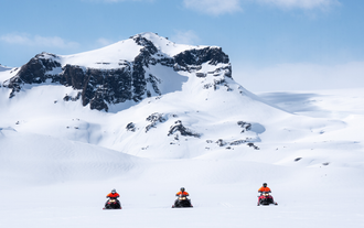 A trio of snowmobile riders exploring the snowy plains of the Langjokull Glacier.
