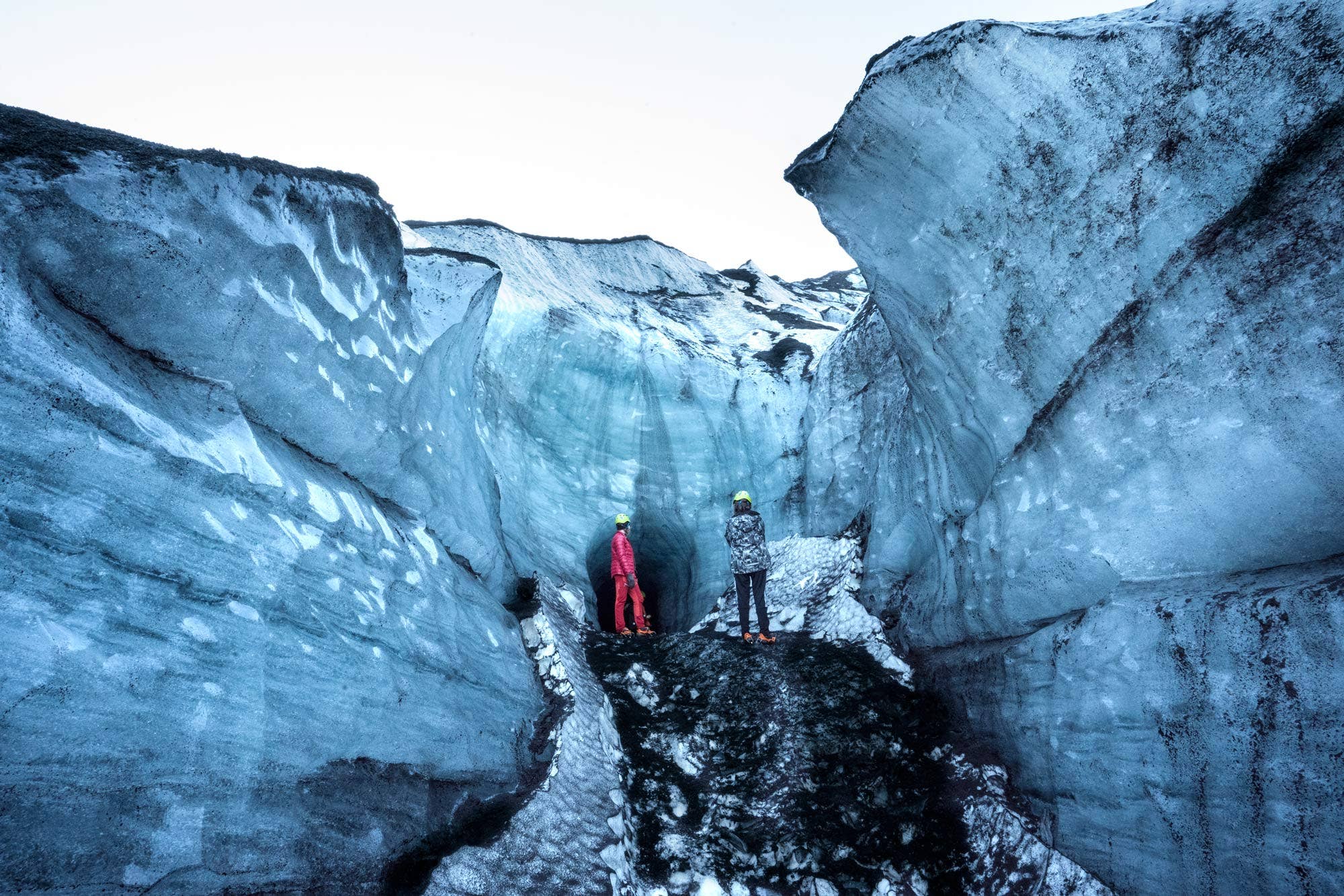Hikers walking through a narrow glacial passage on Katla Glacier.